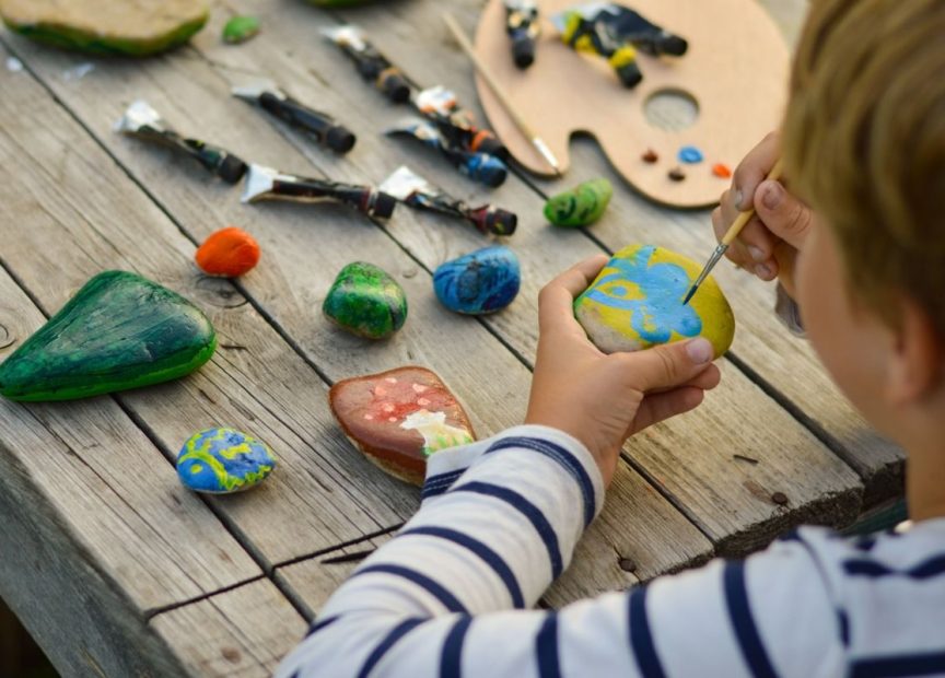 children painting rocks on wooden table
